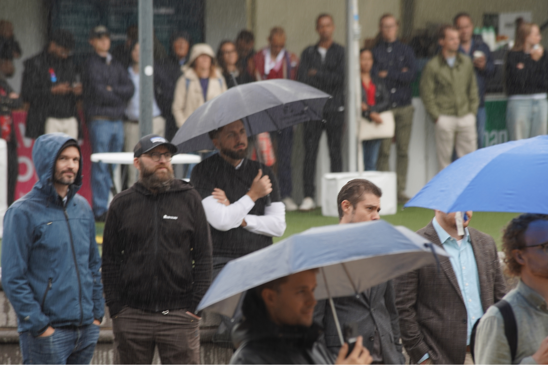 Audience holding umbrellas in the rain at Tech Open